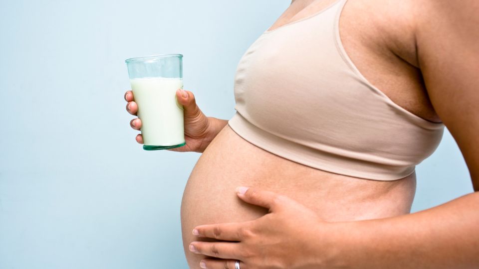 A pregnant woman enjoying a warm cup of turmeric milk in a cozy setting.