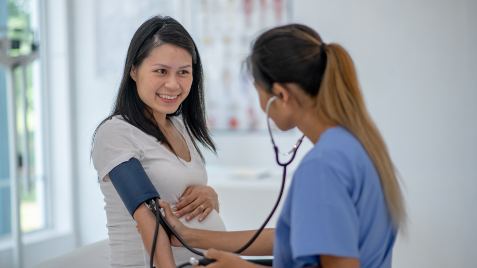 Pregnant woman checking her blood pressure at home