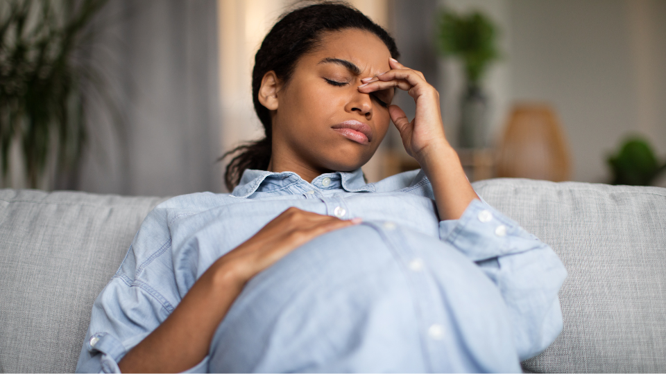 Pregnant woman resting with a cool compress on her forehead