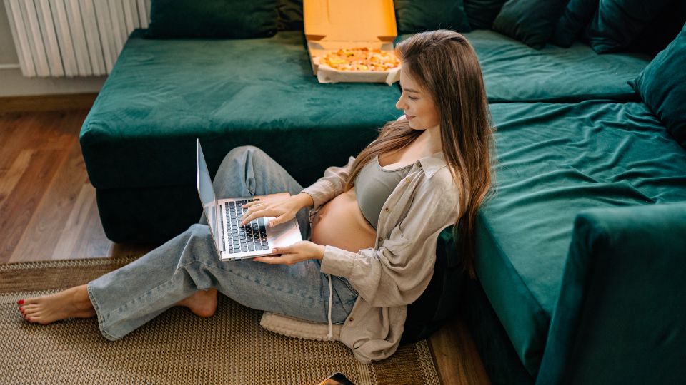 A pregnant woman working on a laptop at a desk, maintaining good posture.