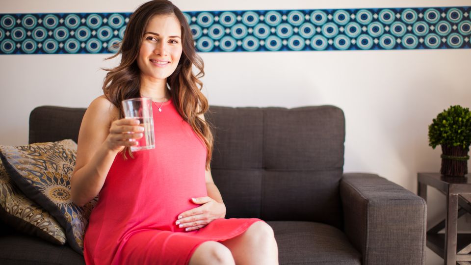 Pregnant woman contemplating drinking a soda.