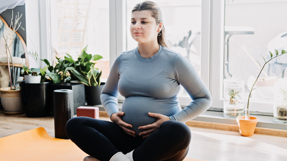 Pregnant woman sitting with a bowl, feeling nauseous