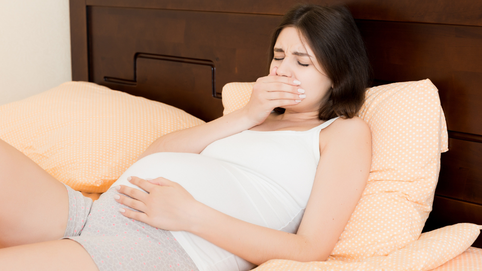 Pregnant woman holding her stomach and looking relieved with natural remedies around her.