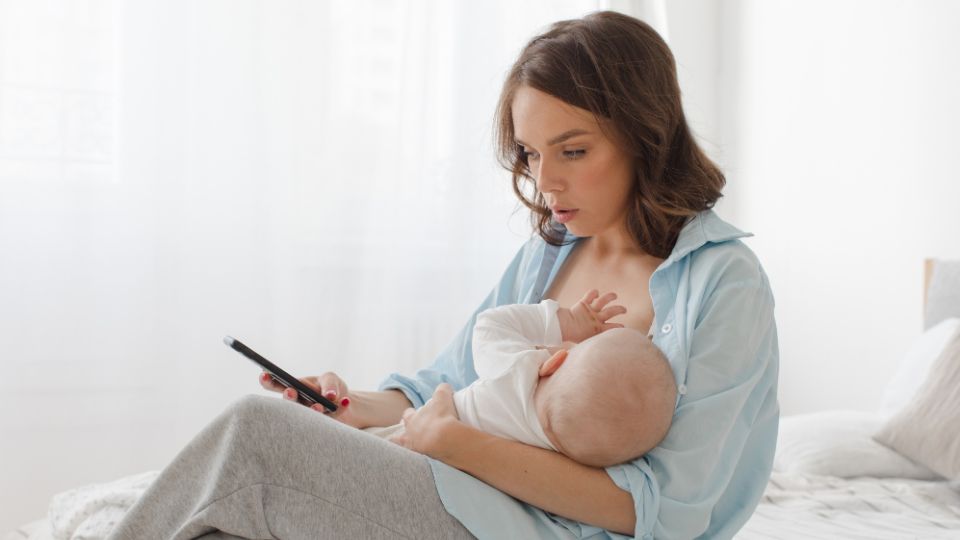 Mother using a mobile phone while breastfeeding