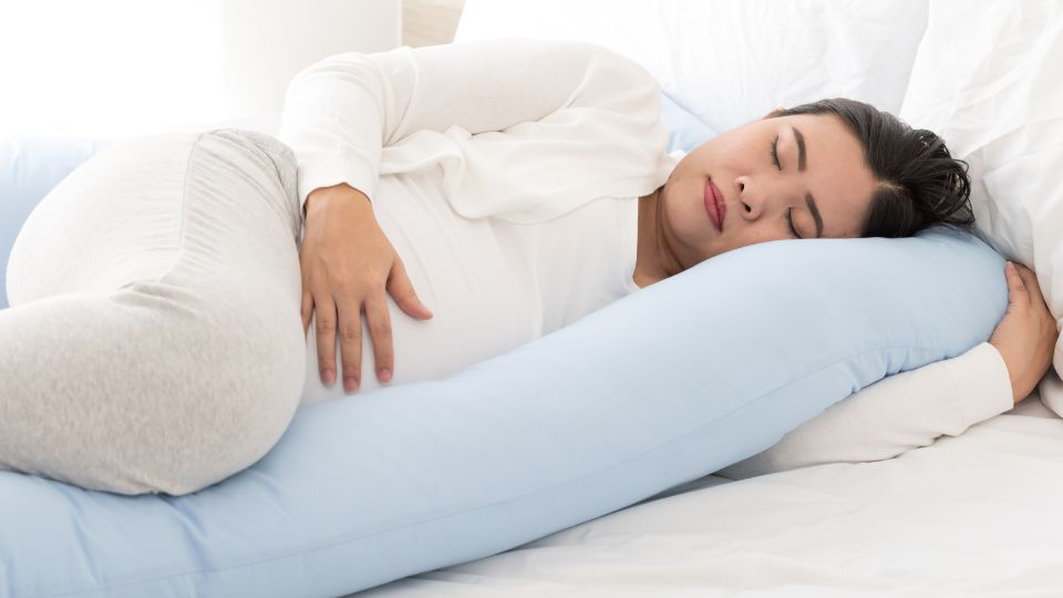 Pregnant woman lying on her back on a bed, appearing relaxed.