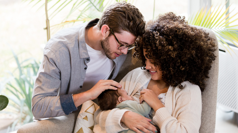 A mother gently trying to breastfeed her baby, who is turning away, illustrating common breastfeeding challenges.