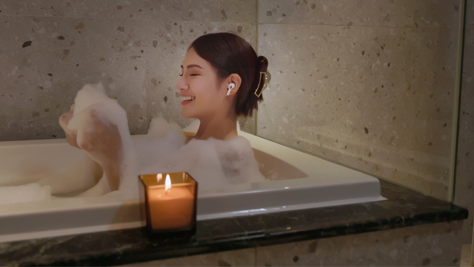 A pregnant woman relaxing in a bathtub filled with warm water and soft lighting.